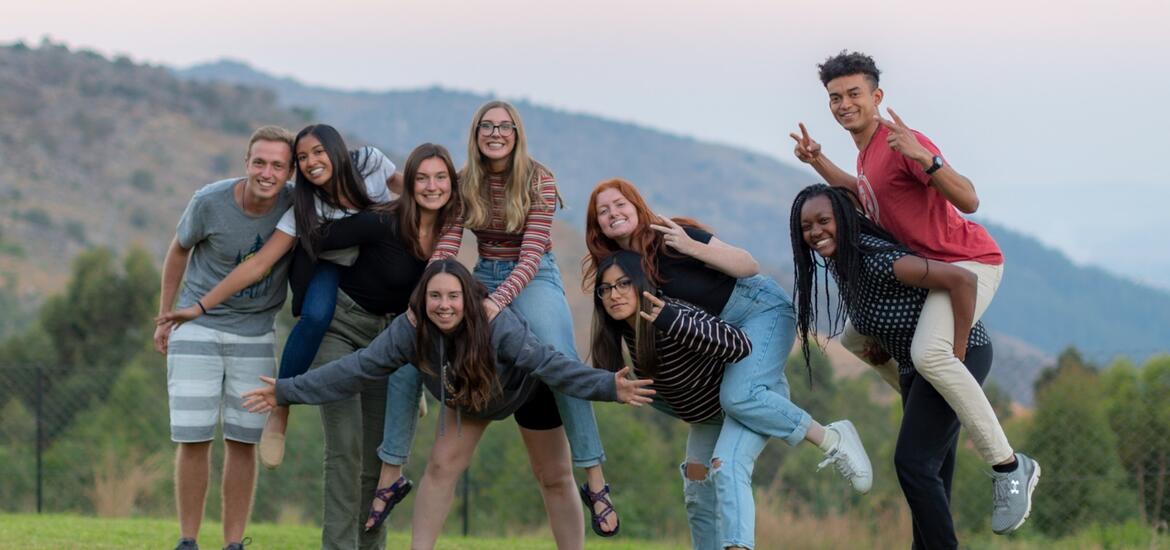 A student with a camera is looking through the door of a medical treatment room, where a doctor is seeing to a patient.