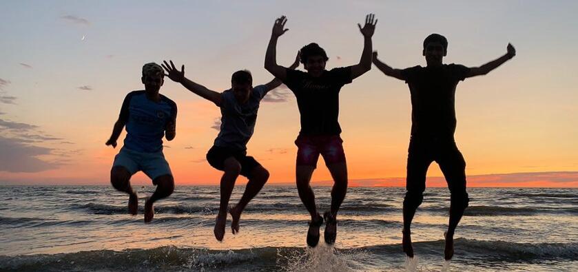 Students jumping during sunset at beach.