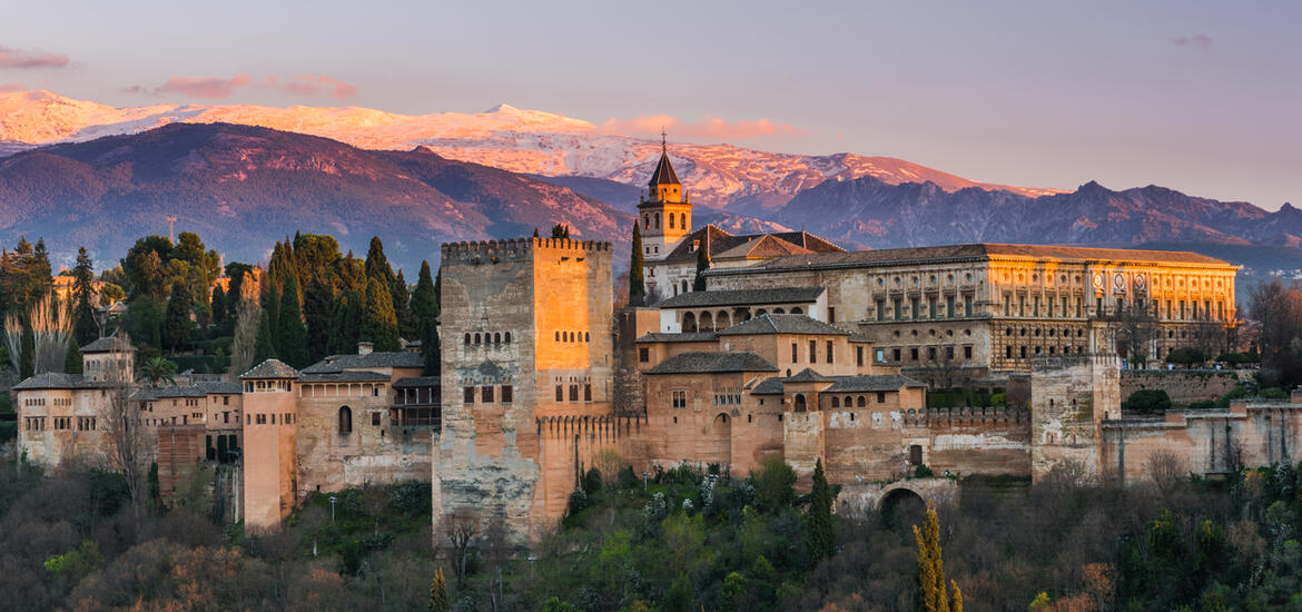 A view of the Alhambra in Granada, Spain, with the snow-capped Sierra Nevada mountains in the background 