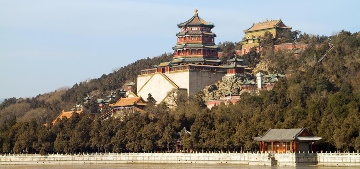 A view of the Summer Palace in Beijing, China, with traditional Chinese architecture set against a hillside surrounded by trees