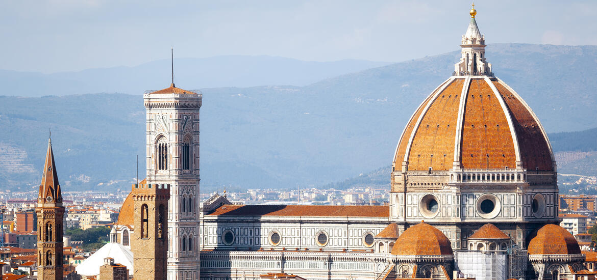 An aerial view of the dome of the Santa Maria del Fiore Cathedral (Duomo) in Florence, Italy, featuring the red-tiled cupola and bell tower 