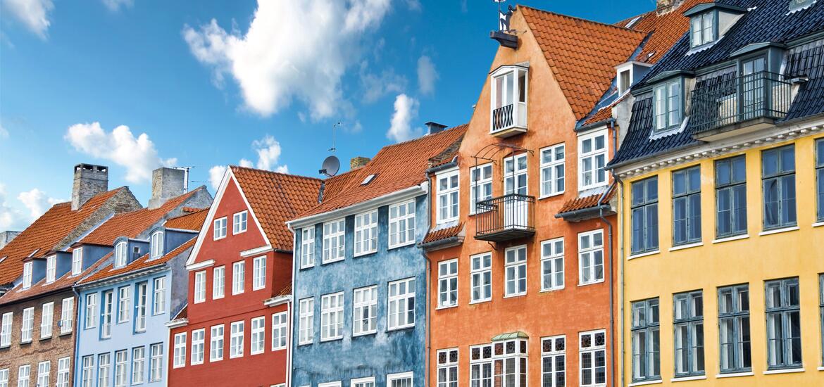 A row of brightly colored Danish houses with traditional red-tiled roofs near the Nyhavn Canal, Copenhagen