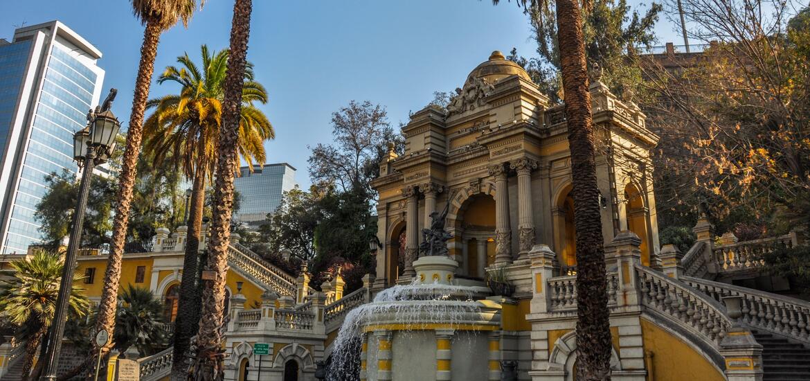 Ornate architecture and palm trees on Santa Lucía Hill in downtown Santiago, Chile, with skyscrapers in the background