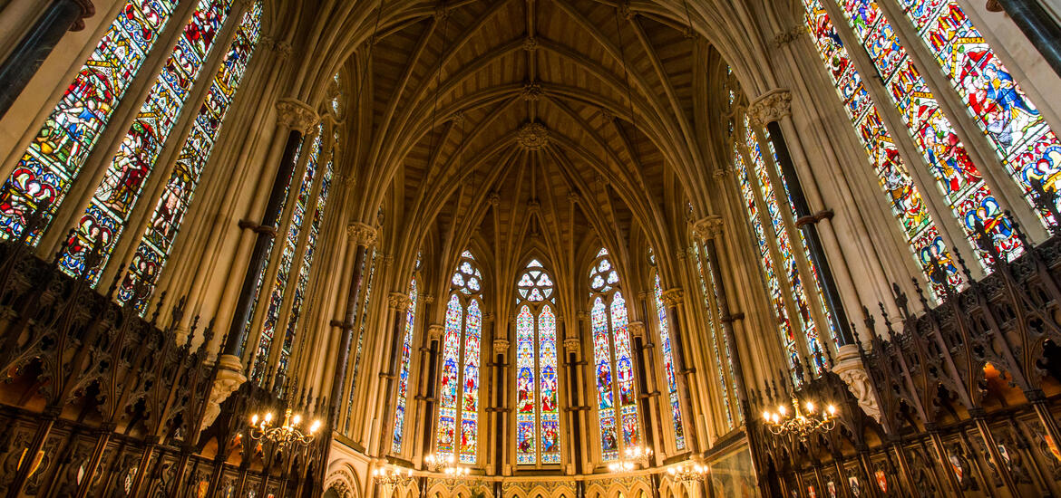 A view of Exeter College Chapel in Oxford, featuring stained glass windows, high vaulted ceilings, and detailed Gothic architectural elements