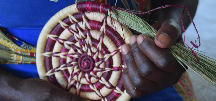 A close-up shot of two hands holding a traditional woven item