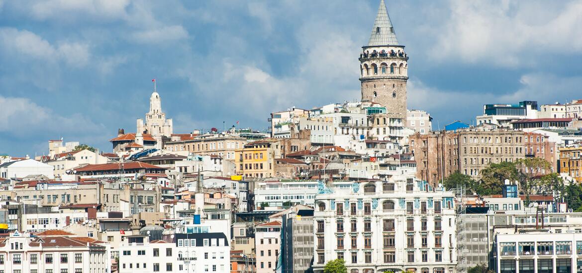 A view of the historic Galata Tower, rising above the buildings of Istanbul, Turkey, with the Golden Horn in the foreground