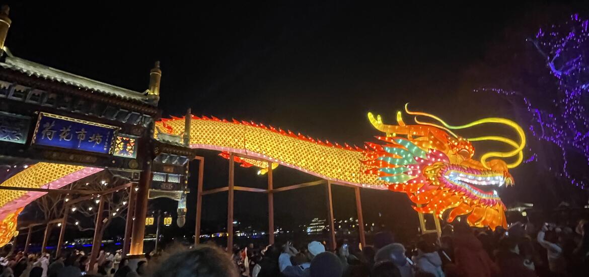 A vibrant illuminated dragon display at the Lantern Festival in Beijing, China, with crowds gathered around it at night