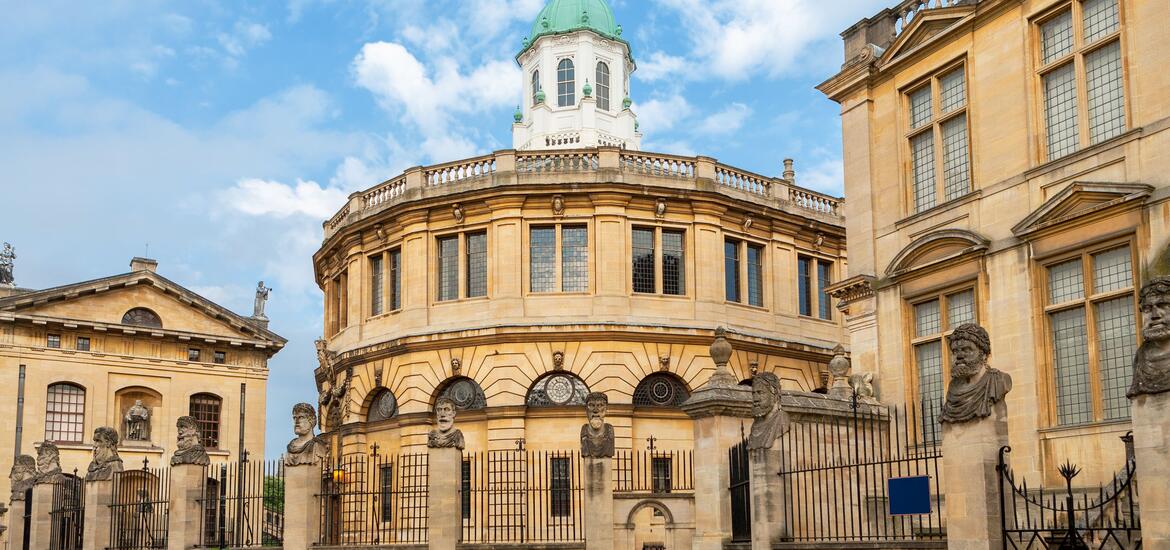 The Sheldonian Theatre in Oxford, a historic domed building with stone statues at the gate