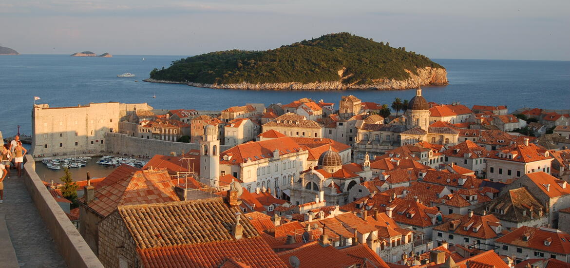 A panoramic view of buildings with red roofs and an island in the background, taken from the city walls of Dubrovnik