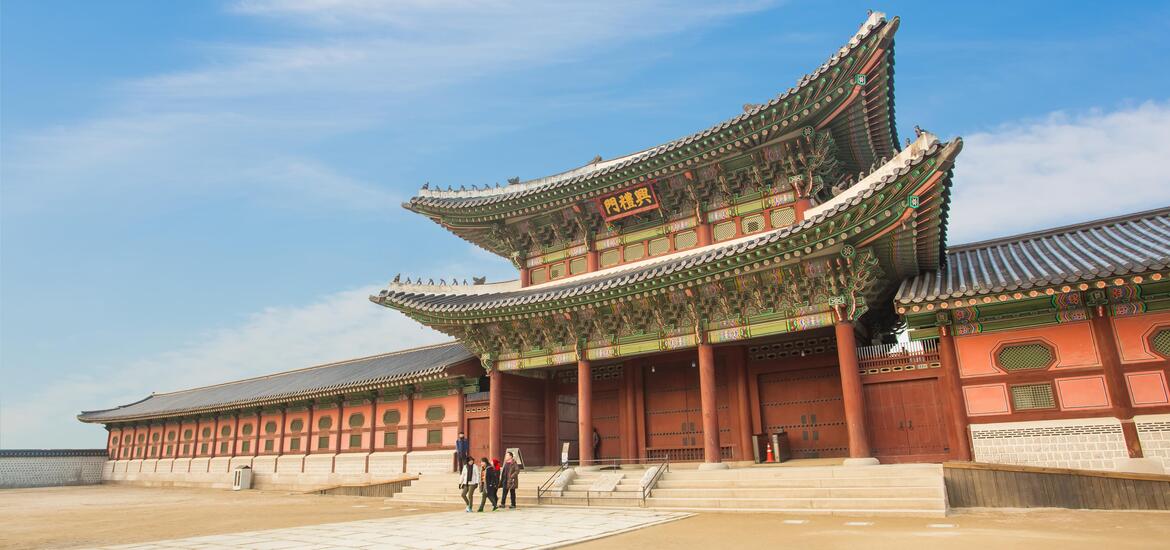 A view of the grand entrance gate of Gyeongbokgung Palace in Seoul, featuring traditional Korean architecture with ornate, colorful details 