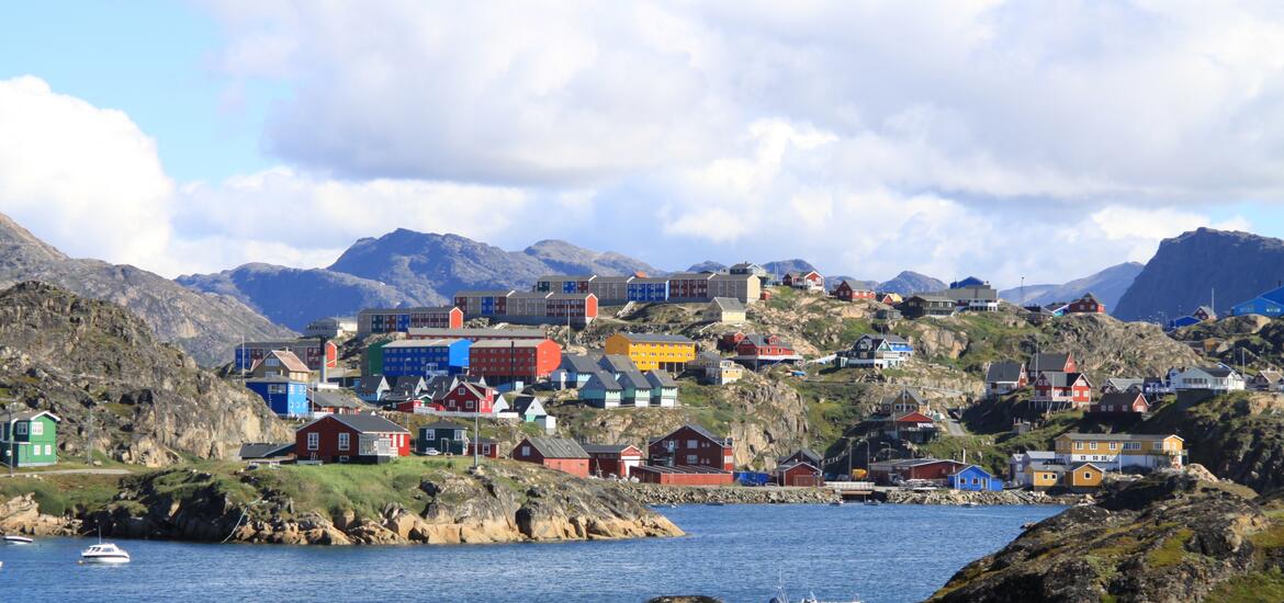 View of houses set into rugged fjord coastline in Greenland