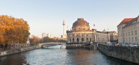 A view of the Bode Museum on Museum Island in Berlin, Germany, with the Spree River in the foreground and the iconic TV Tower in the background