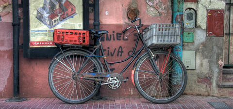 A vintage bicycle with crates attached to its rear wheel, leaning against a graffiti-covered wall in the historic San Telmo district of Buenos Aires, Argentina