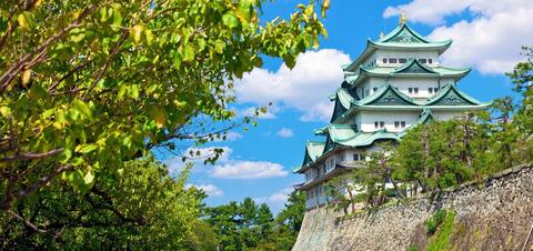 The multi-tiered Nagoya Castle with green-tiled roofs, framed by greenery in Nagoya, Japan