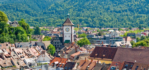 Aerial View of Freiburg, Germany A scenic aerial view of Freiburg, Germany, with its iconic clock tower surrounded by traditional buildings and green hills in the background