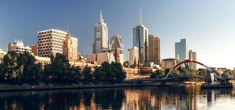 View of the Melbourne skyline with modern skyscrapers and historic buildings, set along the Yarra River under a clear sky