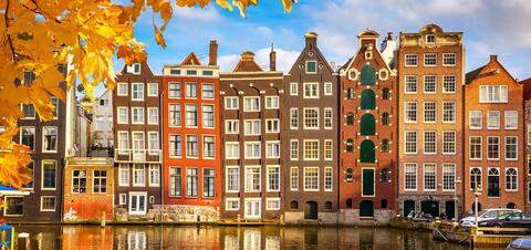 Traditional Dutch canal houses in Amsterdam during autumn, framed by golden leaves