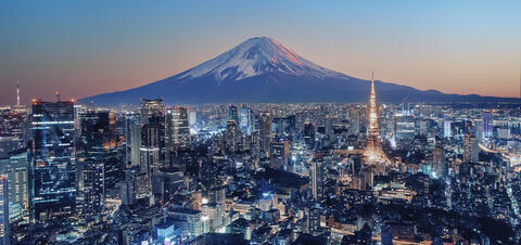 A night view of Tokyo, Japan, with the illuminated Tokyo Tower in the foreground and the majestic Mount Fuji in the background, set against a twilight sky.