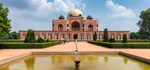 A large red brick tomb with a white dome, surrounded by symmetrical gardens and a reflecting pool, known as Humayun's Tomb, located in New Delhi, India