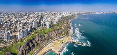An aerial view of Lima's coastline with tall buildings along cliffs overlooking the beach and the Pacific Ocean