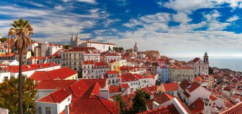 A scenic view of Lisbon's Alfama neighborhood with its iconic red rooftops and historic buildings