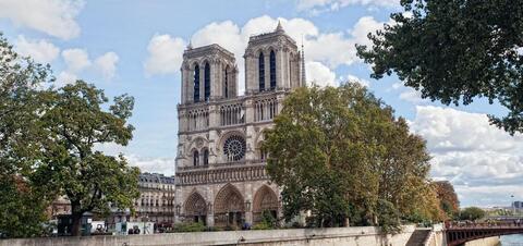 The iconic twin towers of Notre Dame Cathedral rise above the trees along the Seine River in Paris 