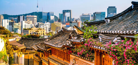 A view of Seoul with traditional-style buildings in the foreground and tall skyscrapers in the distance
