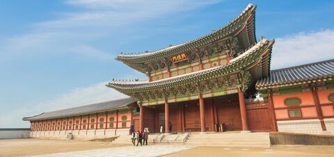 A view of the grand entrance gate of Gyeongbokgung Palace in Seoul, featuring traditional Korean architecture with ornate, colorful details 