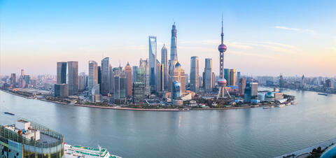Panoramic view of the Shanghai skyline at dusk, featuring modern skyscrapers and the Oriental Pearl Tower along the waterfront