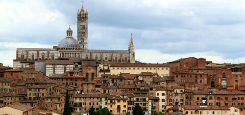 A view of the city of Siena, Italy including the Duomo di Siena cathedral and red brick buildings