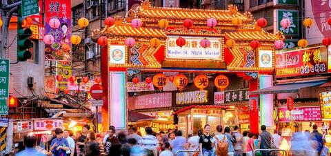 A bustling night market scene at Raohe Street in Taipei, Taiwan, with vibrant neon signs, colorful lanterns, and crowds of people shopping and exploring food stalls.