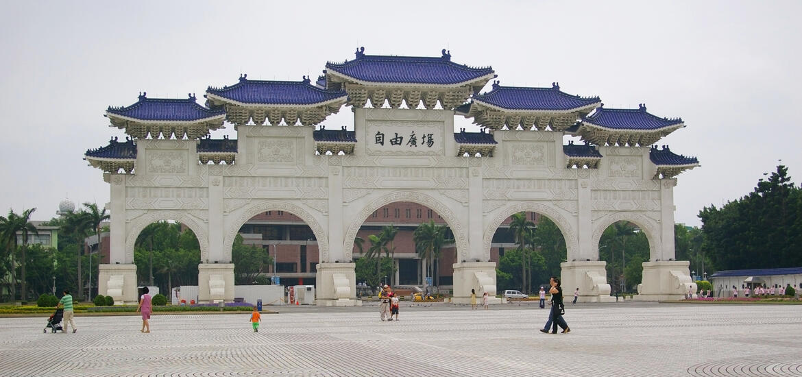 The grand Freedom Square Arch at Chiang Kai-shek Memorial Hall in Taipei, featuring traditional white stone architecture with blue tiled roofs in an open plaze