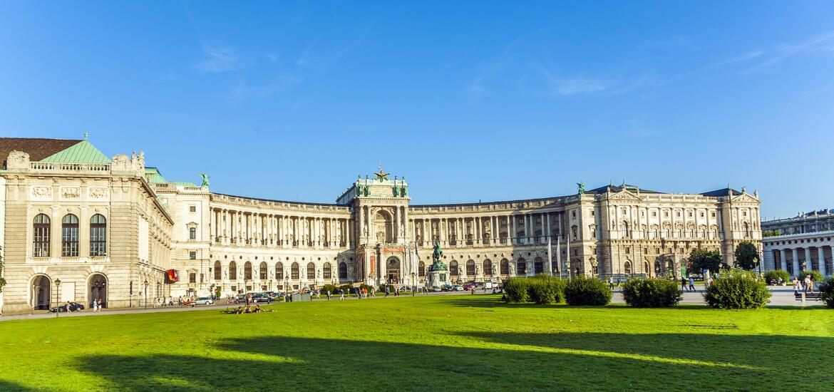 A wide-angle view of Hofburg Palace in Vienna, Austria, showcasing the grand architecture of the historic palace under a bright blue sky