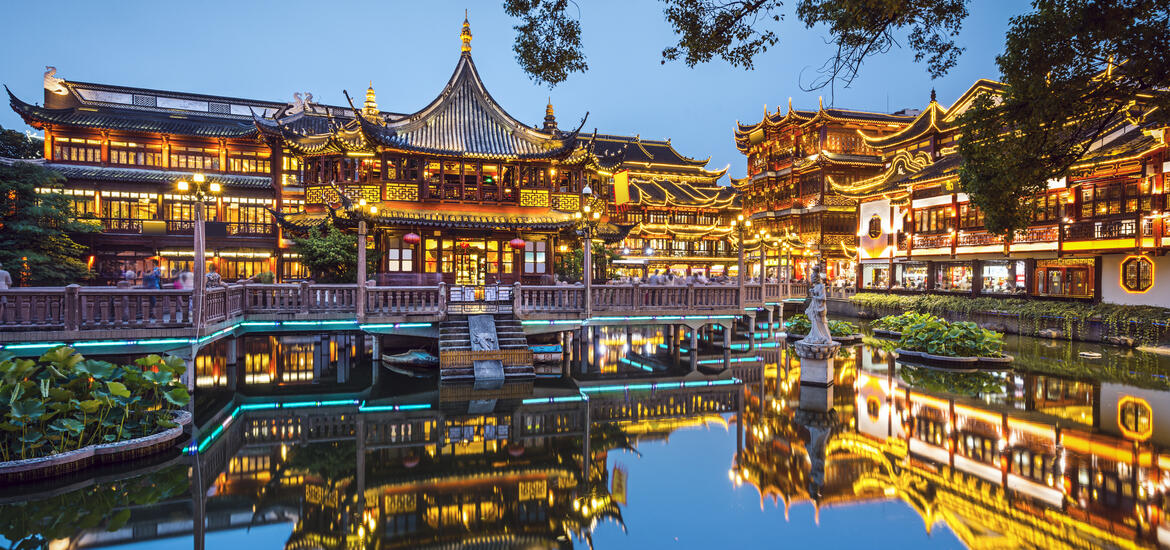 Night view of the illuminated traditional buildings at Yuyuan Gardens in Shanghai, with vibrant reflections in water