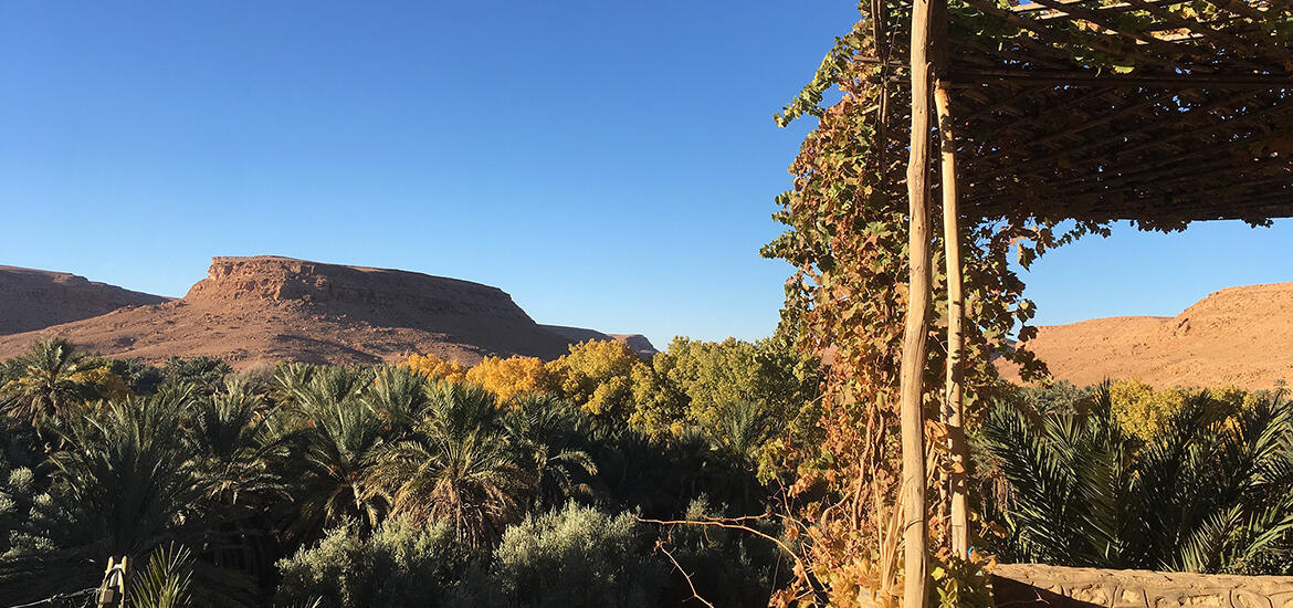 A scenic view of the Akchour Waterfall hike in Morocco, featuring clear green water flowing between rocky cliffs and lush greenery